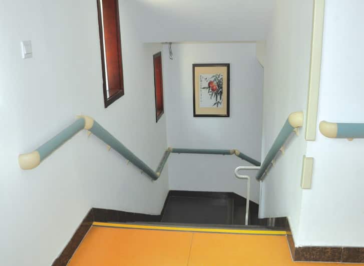 A staircase with PVC wall guards leading to a room with an orange floor.