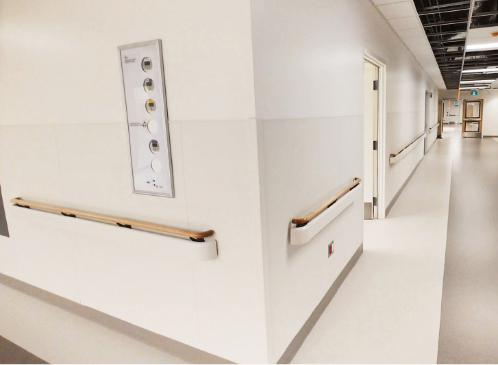 A hospital hallway with white handrails.