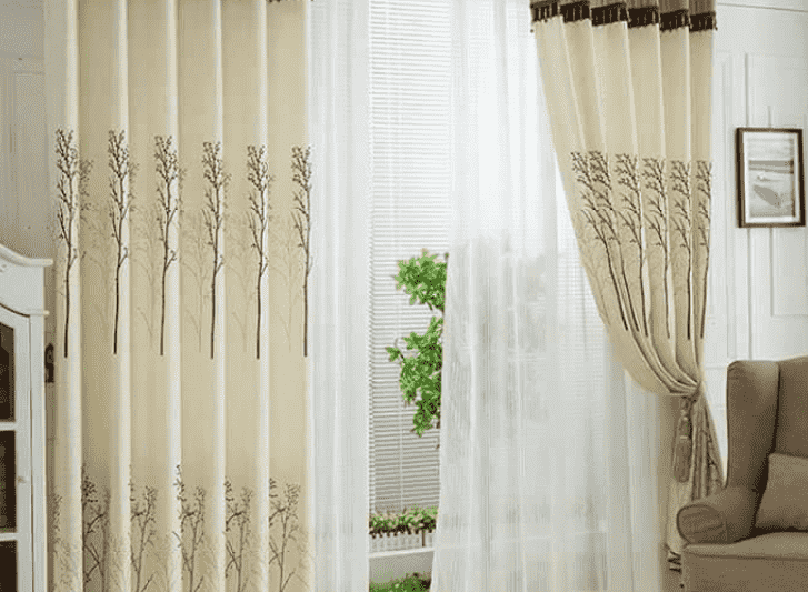 A living room with beige curtains and a chair.